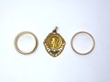 three gold rings and a gold pendant on a white surface