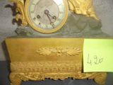 a gold clock sitting on top of a table next to a note
