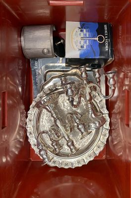 a metal object in a red box with a bottle of wine