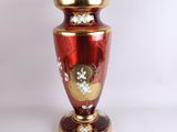a red vase with a gold base and flowers on it