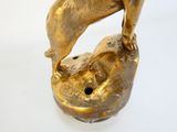 une statue en or représentant un chien et un chat sur un rocher
