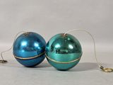 two shiny blue and green christmas ornaments on a white surface