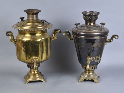 pair of antique brass urns on pedestals on grey background