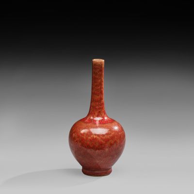 an orange vase sitting on top of a table next to a gray wall