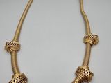un collier plaqué or orné de perles sur un fond blanc