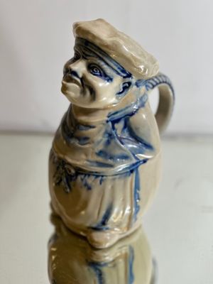 a ceramic figurine of a man wearing a hat and scarf