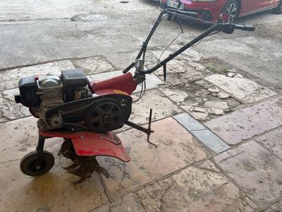 une petite tondeuse à gazon posée sur le trottoir