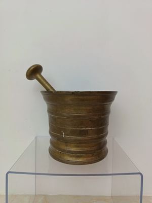 a glass shelf with a brass mortar and a glass bowl on it
