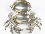 a silver crab shaped object on a white surface