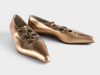 two pairs of gold ballet shoes with laces on them