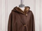 a brown coat with a hood and fur collar on a mannequin dummy