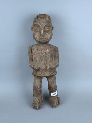 statue d'un homme tenant un morceau de bois et portant une étiquette sur la poitrine