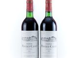 two bottles of red wine sitting next to each other on a white surface