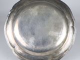 an antique silver plate on a metal stand on a white surface