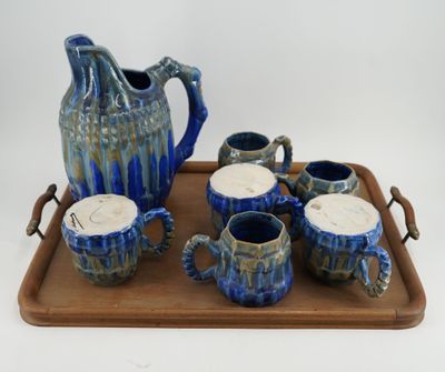 a tray with a pitcher, cups, and tea set on it