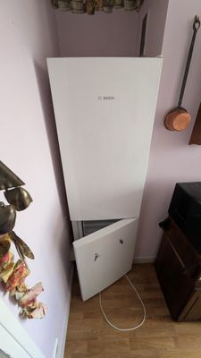 un réfrigérateur blanc dans un coin de la pièce, à côté d'une commode