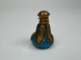 une petite bouteille en verre bleue ornée d'un motif doré