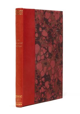 un vieux livre à la couverture rouge posé sur une surface blanche