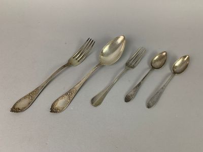 six spoons and a fork are lined up on a table