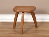 une image représentant un tabouret en bois posé sur un parquet en bois massif
