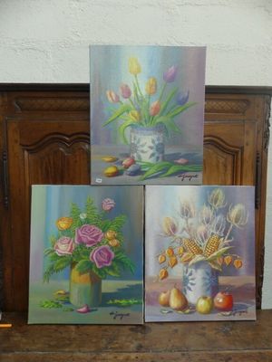 trois tableaux représentant des fleurs dans un vase posé sur une table en bois