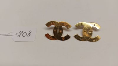 une paire de boucles d'oreilles Chanel posées sur une surface blanche
