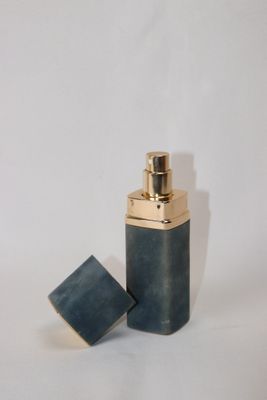 un petit flacon de parfum posé sur une surface blanche