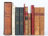 several old books are lined up in a row on a white surface