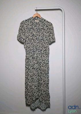 black and white floral dress hanging on a hanger in front of a white wall