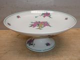 un bol blanc orné de fleurs roses, posé sur une table en bois