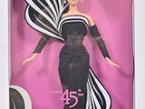 La poupée Barbie se trouve dans une boîte, vêtue d'une robe noire et blanche.