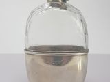 a small glass bottle with a silver lid on a table