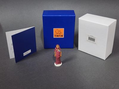 une figurine représentant une femme en robe rose à côté d'une boîte bleue