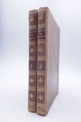 two old books sitting on top of each other on a white surface