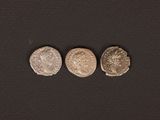 three ancient roman coins on a black background