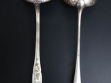 two silver spoons and a fork on a black surface
