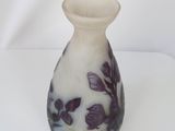 a white vase with purple flowers on it sitting on a table