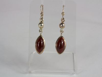 a pair of silver and red stone earrings on a clear display