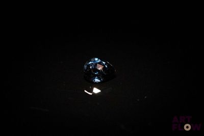 a close up of a blue diamond sitting on top of a black surface
