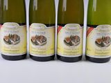 four bottles of wine are lined up on a white surface