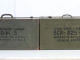 pair of vintage military ammo cans sitting on top of a white table