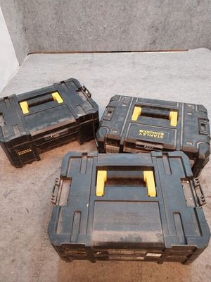 trois coffres à outils noirs et jaunes posés par terre les uns à côté des autres