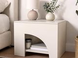 une table blanche sur laquelle est posée une lampe, à côté d'un lit