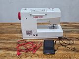 a white sewing machine on a wooden table with a red cord