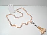 collier avec des perles et un pompon posé sur une table blanche