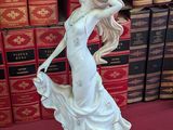 a figurine of a woman holding a dog in front of a stack of books