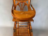 an old wooden high chair with a wicker seat on top of it