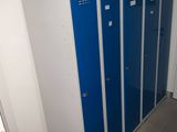 Plusieurs casiers bleus sont alignés le long d'un mur dans une pièce