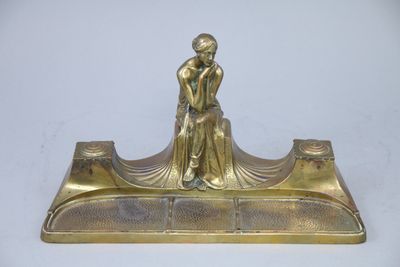 brass figurine of a woman sitting on a bench