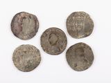 five silver coins of different sizes and shapes on a white surface